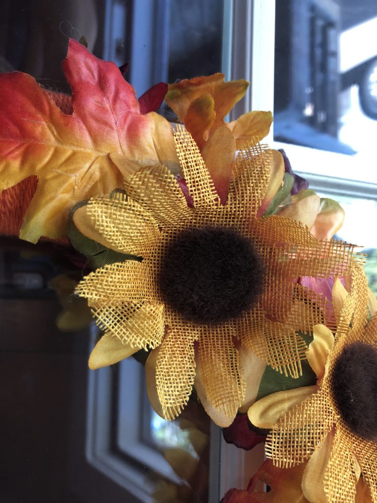 a close-up of sunflowers and fall leaves on a wreath