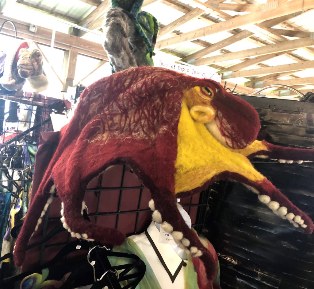 a large red octopus, made of felted wool, is draped across a display