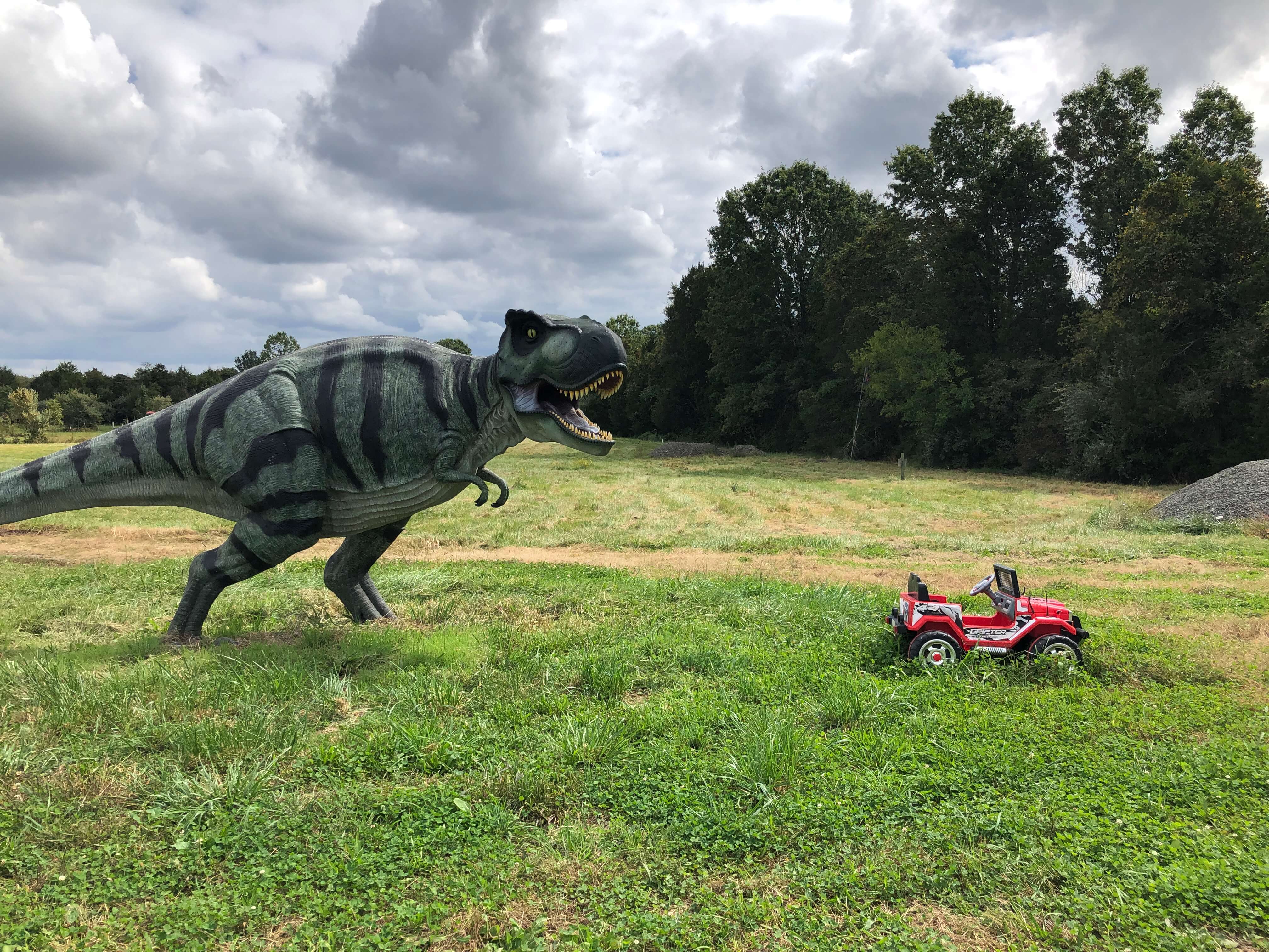 a tyrannosaurus rex appears to chase a Power Wheels Jeep