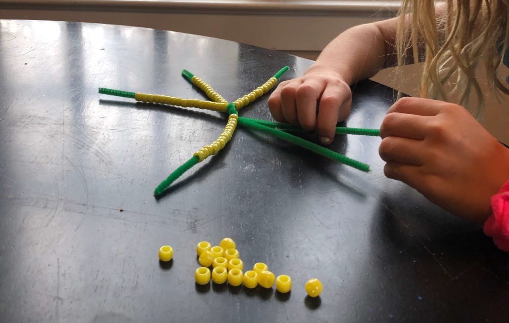 little fingers string pony beads onto chenille stems (aka pipe cleaners)