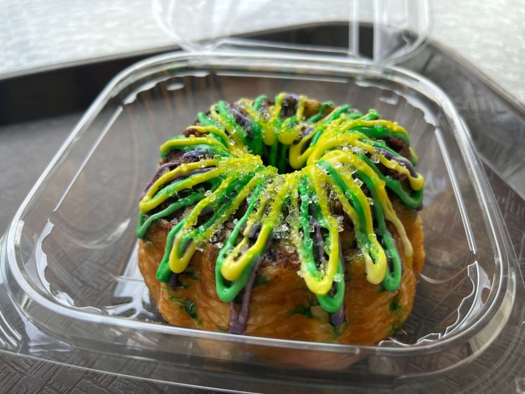 a small pound cake cooked in a baby Bundt pan covered with frosting and crystal sugar